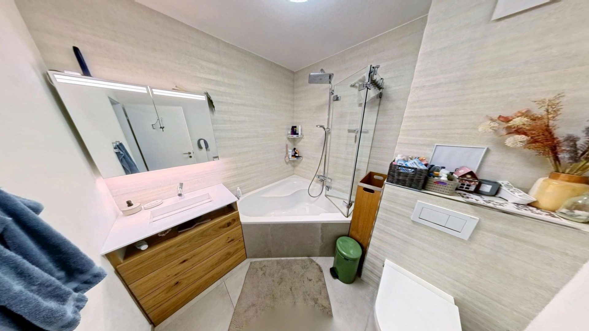 Badezimmer mit Eckbadewanne, Dusche hinter Glas und Waschtisch aus Eiche