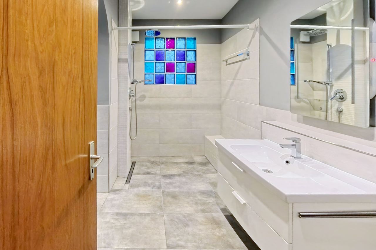Badezimmer mit bodenebener Dusche, Glasbausteinen und Waschtisch