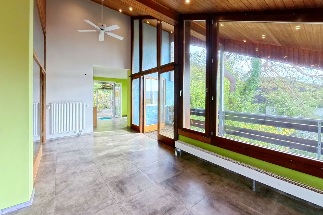 Wohnbereich mit Fensterfront zum Balkon und Deckenventilator